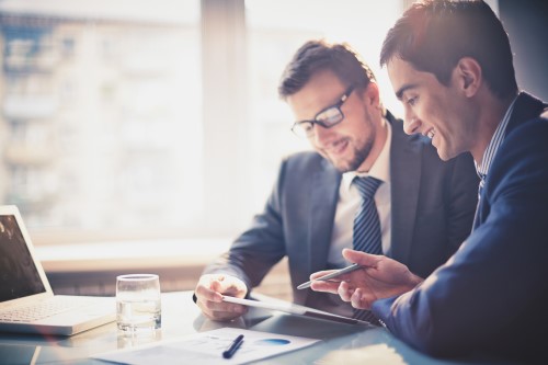 two dudes huddled over chatting about finance it consulting services